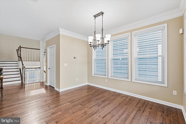 unfurnished dining area featuring dark wood-style floors, ornamental molding, baseboards, and an inviting chandelier