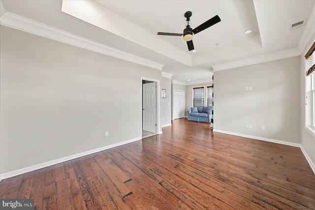 unfurnished room featuring visible vents, baseboards, ornamental molding, dark wood-style floors, and a tray ceiling