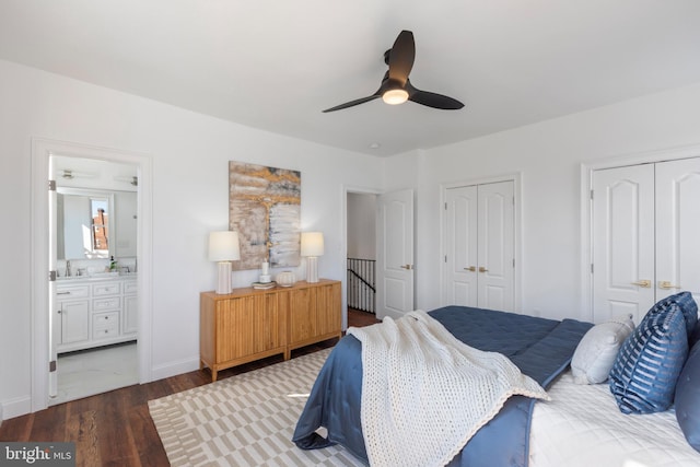 bedroom with connected bathroom, wood finished floors, a ceiling fan, baseboards, and multiple closets