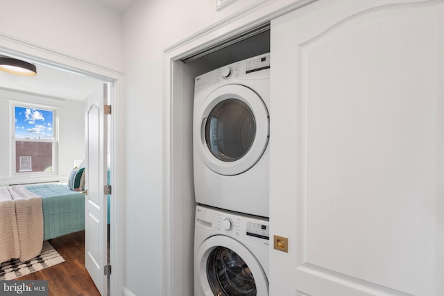 laundry room with stacked washer and dryer and dark wood-style flooring