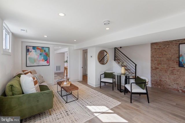 living area featuring recessed lighting, brick wall, visible vents, light wood-style floors, and stairs