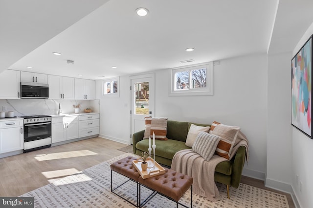 living area with visible vents, recessed lighting, light wood-style flooring, and baseboards