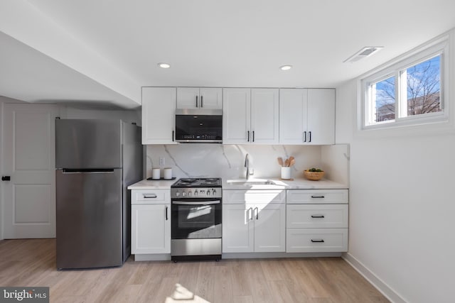 kitchen featuring light countertops, appliances with stainless steel finishes, a sink, and visible vents