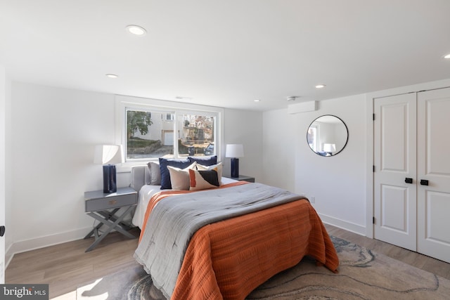 bedroom featuring light wood finished floors, a closet, recessed lighting, and baseboards