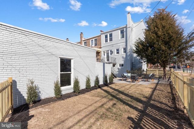 rear view of property with a patio area, brick siding, a lawn, and a fenced backyard