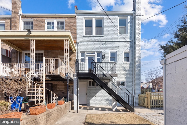 rear view of house featuring brick siding and stairs