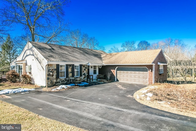 view of front of home with driveway, stone siding, roof with shingles, and an attached garage