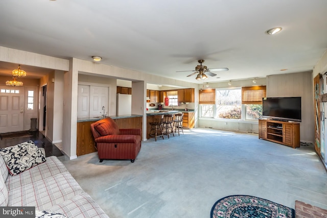 living room with light carpet, baseboards, and ceiling fan with notable chandelier