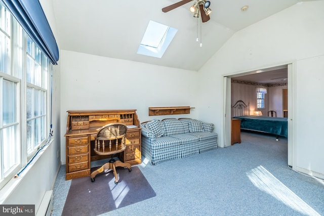 carpeted office featuring lofted ceiling with skylight, baseboard heating, and a ceiling fan