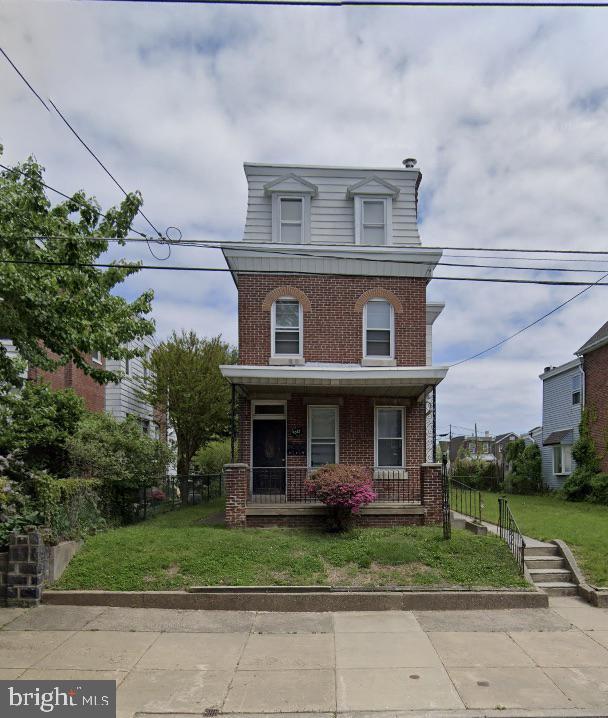 view of front of home featuring covered porch, brick siding, a front lawn, and fence