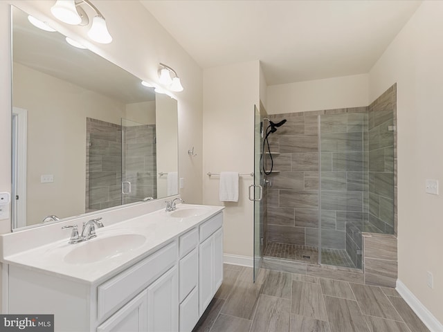 full bath featuring a stall shower, a sink, baseboards, and double vanity