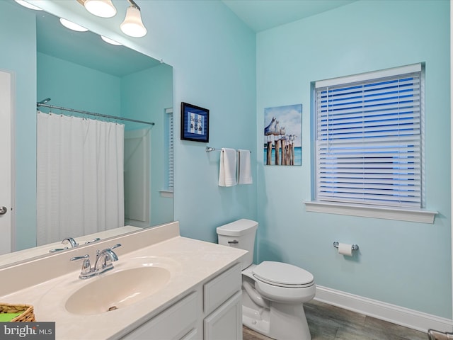 bathroom with baseboards, a shower with shower curtain, toilet, wood finished floors, and vanity