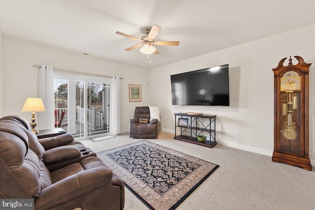 carpeted living area with ceiling fan and baseboards