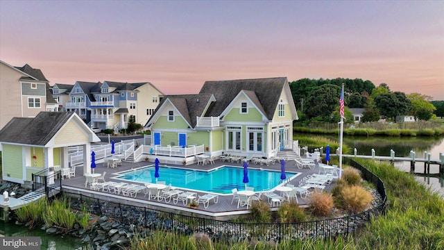 pool with a water view, a fenced backyard, a storage structure, and an outbuilding