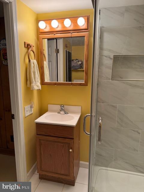 bathroom featuring tile patterned flooring, a shower stall, vanity, and baseboards