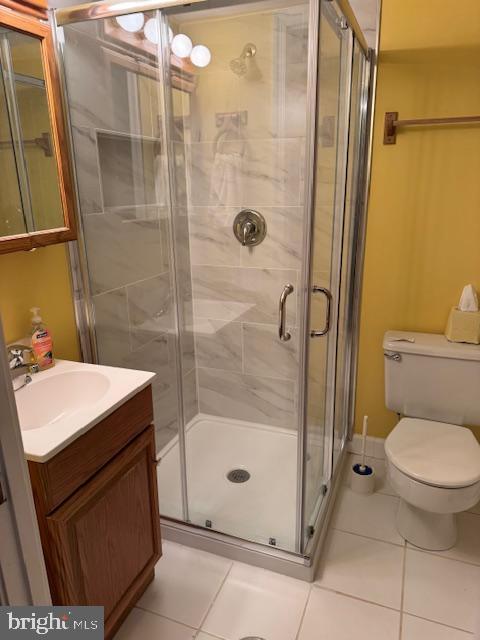 bathroom featuring a stall shower, vanity, toilet, and tile patterned floors