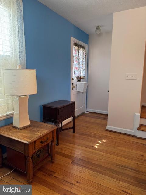 living area with a textured ceiling, baseboards, and wood finished floors