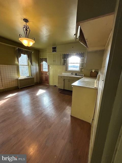 kitchen with dark wood-type flooring, open floor plan, light countertops, radiator, and decorative light fixtures