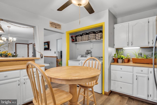 dining area with light wood-style floors, washing machine and clothes dryer, and ceiling fan with notable chandelier