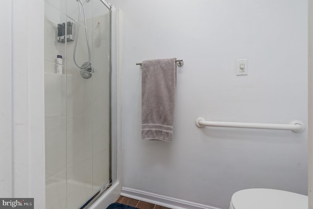 full bathroom with toilet, a stall shower, baseboards, and wood finished floors