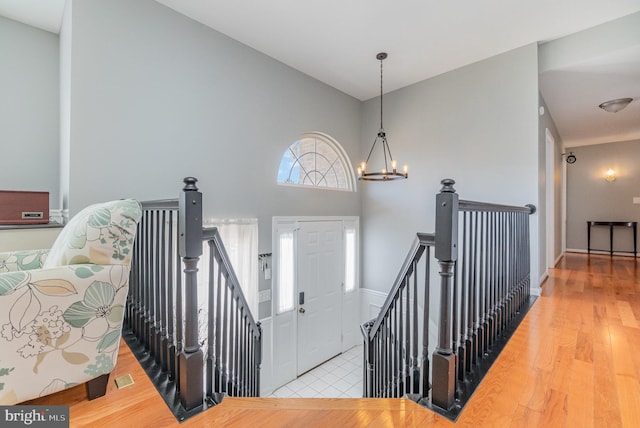 entrance foyer featuring wood finished floors, visible vents, a towering ceiling, and an inviting chandelier