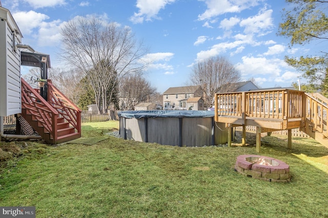 view of yard featuring an outdoor fire pit, fence, a covered pool, a wooden deck, and stairs