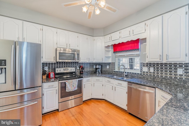 kitchen featuring appliances with stainless steel finishes, white cabinets, a sink, and light wood-style flooring