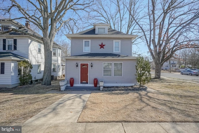 traditional style home with a front lawn and roof with shingles