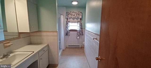 bathroom featuring toilet, baseboard heating, a stall shower, wainscoting, and vanity