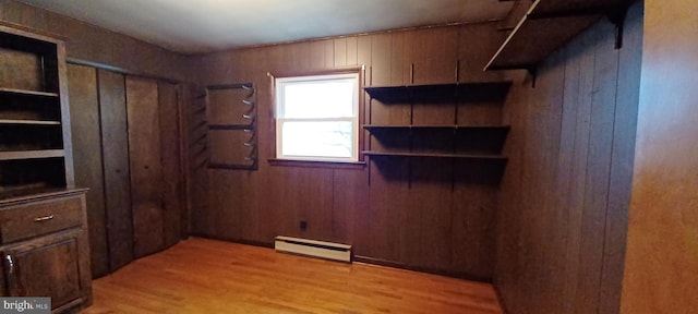 interior space featuring light wood finished floors, wood walls, and a baseboard radiator