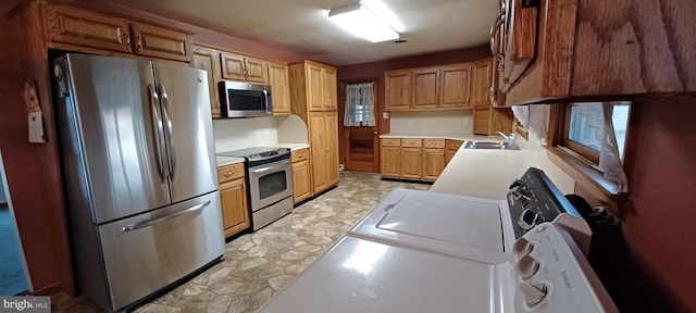 kitchen with appliances with stainless steel finishes, light countertops, a sink, and light floors