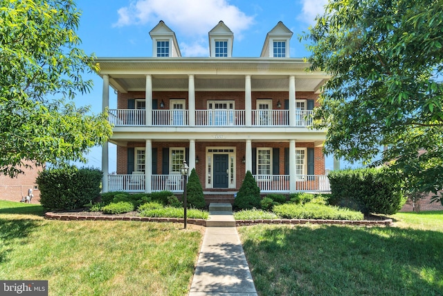 neoclassical home featuring a front lawn, a porch, and brick siding