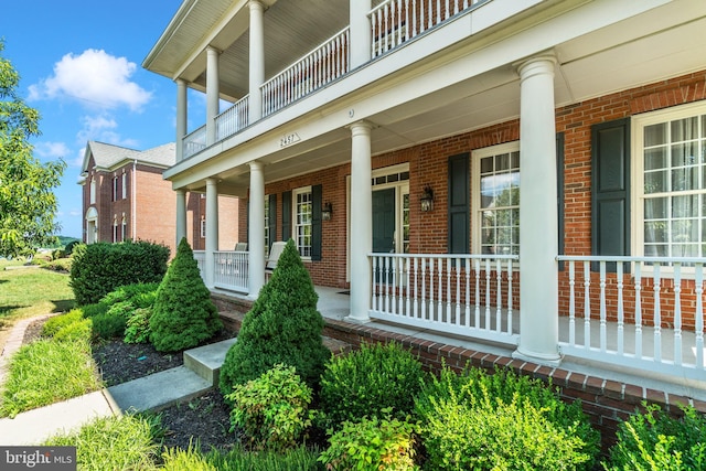 doorway to property featuring covered porch and brick siding