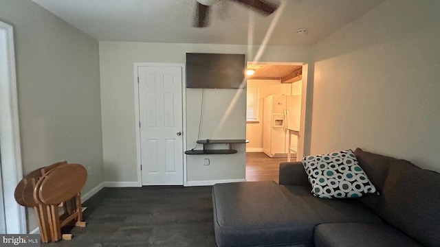 living room featuring a ceiling fan, baseboards, and wood finished floors