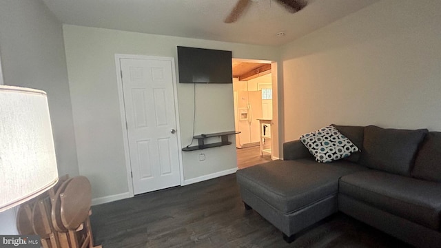 living room with dark wood-type flooring, ceiling fan, and baseboards