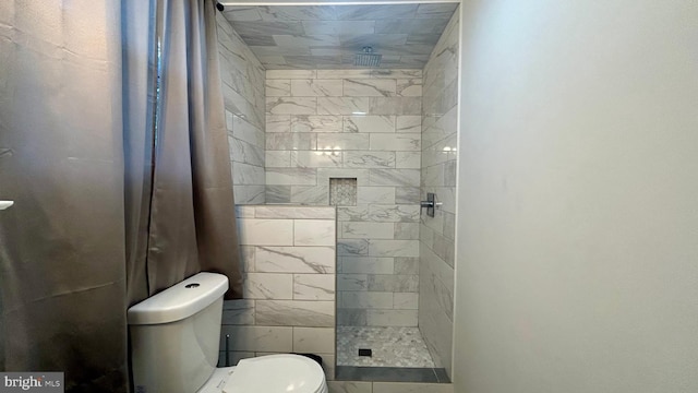 bathroom featuring a tile shower and toilet