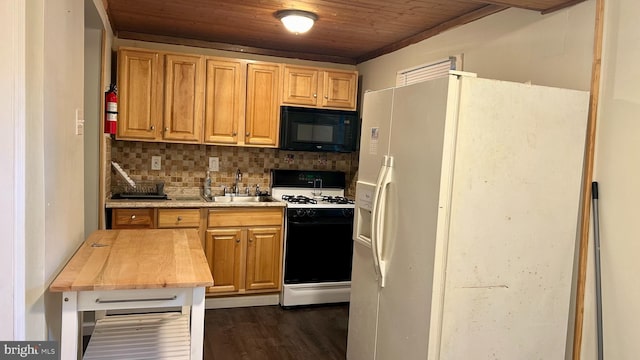 kitchen featuring decorative backsplash, a sink, gas range, white fridge with ice dispenser, and black microwave