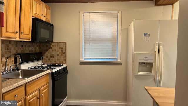 kitchen featuring black microwave, white refrigerator with ice dispenser, a sink, tasteful backsplash, and gas range oven