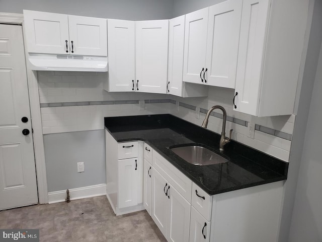 kitchen with under cabinet range hood, white cabinetry, backsplash, and a sink