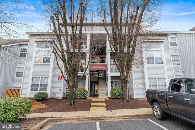 view of property featuring uncovered parking and stairway