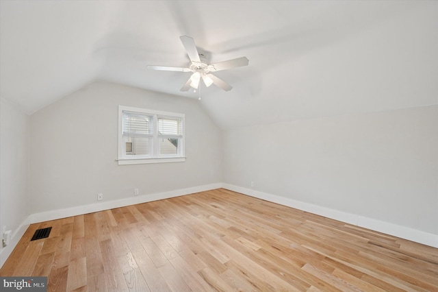 bonus room with light wood-type flooring, visible vents, vaulted ceiling, and baseboards