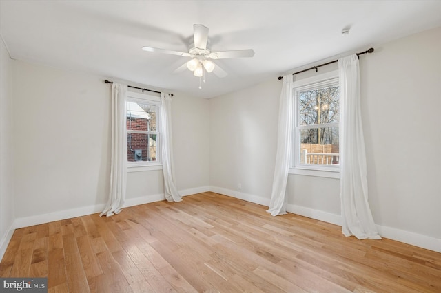 spare room featuring a ceiling fan, baseboards, and light wood finished floors