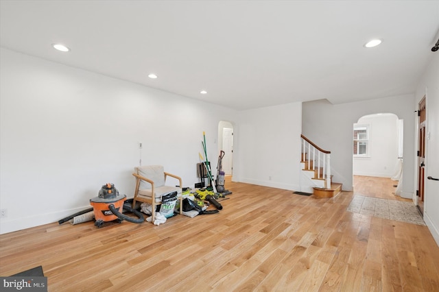 exercise room featuring light wood-type flooring, arched walkways, baseboards, and recessed lighting