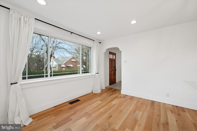 spare room featuring arched walkways, recessed lighting, visible vents, light wood-type flooring, and baseboards