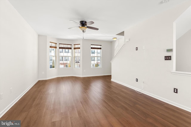 unfurnished living room with ceiling fan, dark wood-style flooring, and baseboards