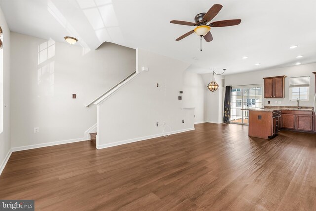 unfurnished living room with dark wood-style floors, a sink, stairway, and baseboards