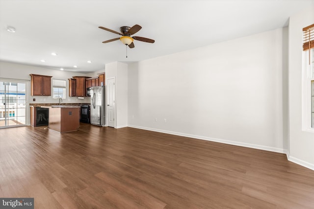 unfurnished living room with recessed lighting, dark wood-type flooring, a ceiling fan, a sink, and baseboards