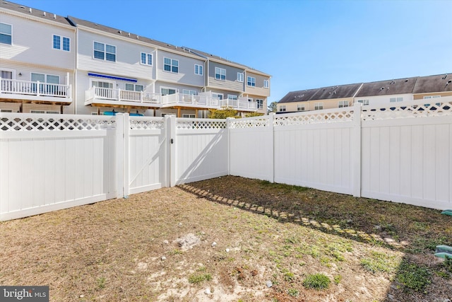 view of yard with a residential view, a fenced backyard, and a gate