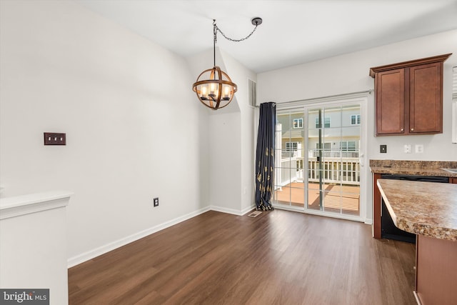 unfurnished dining area featuring dark wood-style floors, baseboards, and a notable chandelier