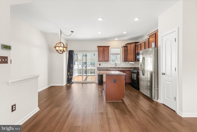 kitchen featuring dark wood-type flooring, a center island, a notable chandelier, black appliances, and a sink